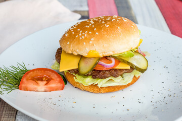 Burger with meat patty, cheese and vegetables side view