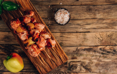 Grilled chicken on bamboo skewers with basil on rustic wooden background.