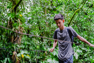 latin teenager in the jungle crossing a hanging bridge, ecological hike in colombia