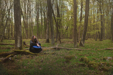 A man sitting in the forest playing a tongue drum - musical instrument with unique sound. It is very similar to a musical instrument called a handpan, hang or pantam.
