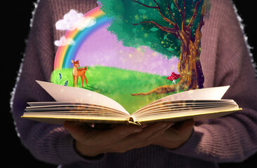 Girl holding open book with drawn magic forest against dark background, closeup