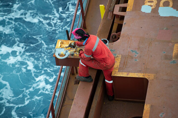 Fototapeta na wymiar Seaman ship crew priming and derusting vessel deck for upcoming painting.