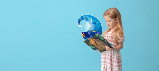 Funny little girl holding book with drawn sea wave on blue background