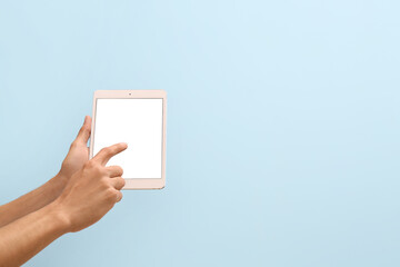 Male hands with modern tablet computer on color background