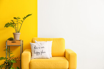 Comfortable armchair and beautiful houseplants near color wall