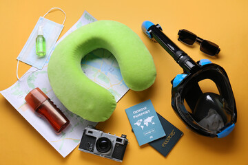Beach accessories with snorkeling mask, neck pillow, photo camera and immune passport on orange...