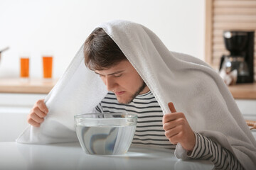 Young man doing steam inhalation at home to soothe and open nasal passages