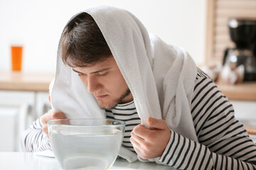Young man doing steam inhalation at home to soothe and open nasal passages - obrazy, fototapety, plakaty