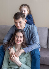 Lifestyle family. Mom dad and daughter are sitting on the couch and hugging.