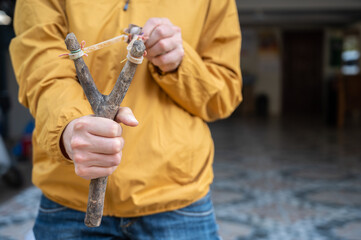 Someone using a wood slingshot for shooting somethings. and A slingshot works like a small catapult, with rubber strips holding a stone or other projectile sits.