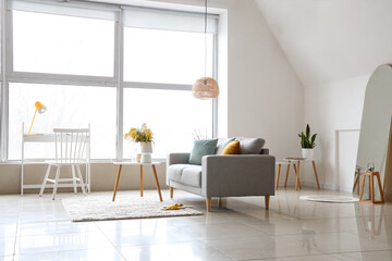 Vase with mimosa flowers on table and sofa in interior of living room