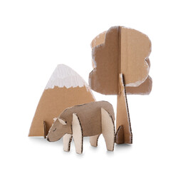 Handmade cardboard bear near tree and mountain on white background