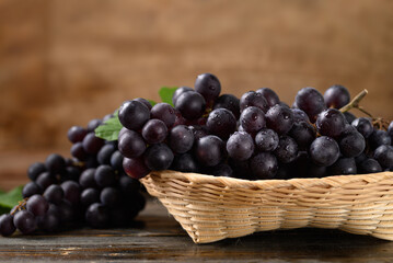 Red grape in bamboo basket on wooden background