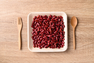 Red kidney bean on plate with spoon and fork on wooden background, Table top view