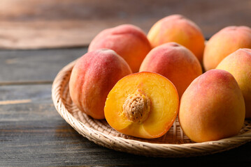 Naklejka na ściany i meble Peach fruit in basket on wooden background