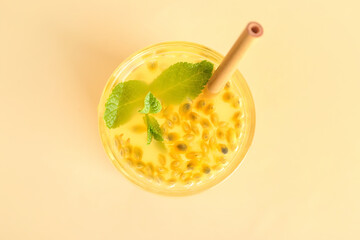 Glass of delicious passion fruit juice on yellow background