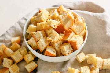 Bowl with tasty croutons and napkin on white background, closeup