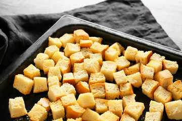 Baking dish with tasty croutons and napkin on white background, closeup