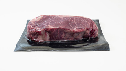 A raw piece of beef for steak in vacuum packaging isolated on white background. High-quality photo.