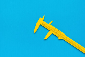 A yellow plastic caliper on a blue background.