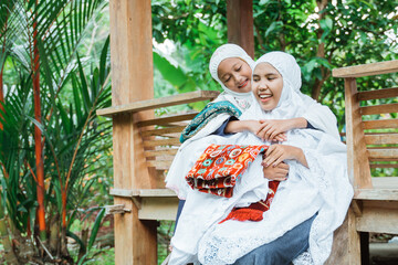 beautiful portrait of mother and daughter wearing mukena. asian muslim smiling to camera before praying to the mosque