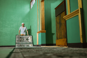portrait of asian muslim young male cleaning the mosque before praying