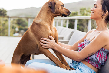 Shot of a beautiful young woman relaxing with her pet dogs outdoors on sofa.