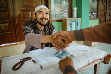 Religious Muslim man shake hand after giving donation and zakat at the mosque during ramadan