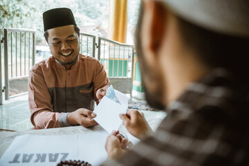 portrait of happy muslim man paying zakat for eid mubarak at the mosque