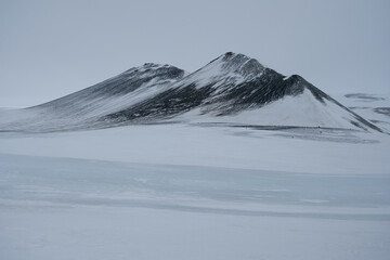Winterly scenery with snow capped mountains steep rocks cliffs with glaciers, waterfalls and coastal line in magic mystical cloudy day dramatic clouds cloudscape in Seydisfjordur, Iceland with snow © Tamme Wichmann