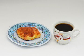  croissant on a white plate and a cup of coffee
