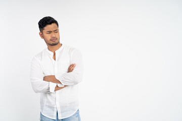 sad asian young man wearing white shirt with arms crossed on isolated background