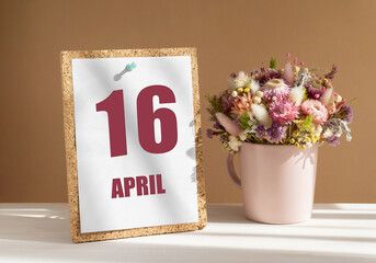 April 16. 16th day of month, calendar date.Bouquet of dead wood in pink mug on desktop.Cork board with calendar sheet on white-beige background. Concept of day of year, time planner, spring month