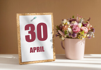 April 30. 30th day of month, calendar date.Bouquet of dead wood in pink mug on desktop.Cork board with calendar sheet on white-beige background. Concept of day of year, time planner, spring month