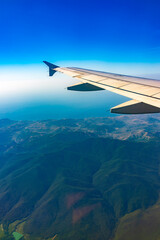 Fototapeta premium View from the airplane window at a beautiful blue clear sky and the airplane wing