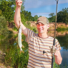 A young fisherman with a pike and spinned on a river