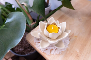 A beeswax tealight candle is inside of a flower shaped holder. - obrazy, fototapety, plakaty