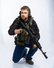 airsoft player in full gear is ready to play. a man in an outfit, in headphones, a bulletproof vest, with a backpack and a belt with additional shells. on a white background.