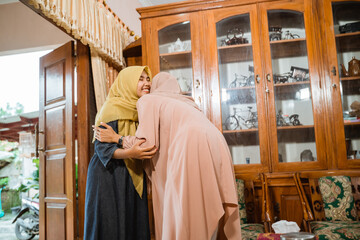 beautiful muslim woman hug and kissing each other during family visit at home on idul fitri celebration