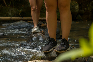 Lower shot of two girls walking over river rocks