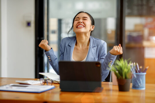 Portrait of Happy excited Asian businesswoman looking on a tablet laptop screen at workspace,