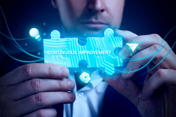 Obraz premium Business, Technology, Internet and network concept. Young businessman working on a virtual screen of the future and sees the inscription: Continuous improvement