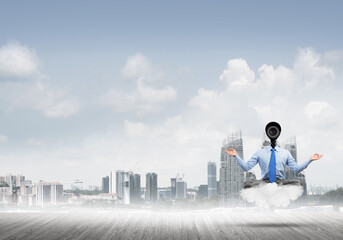 Camera headed man sitting in lotus pose on cloud against modern cityscape