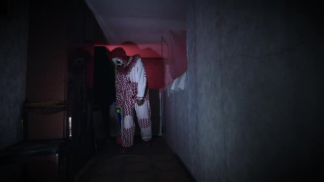 Creepy and evil clown, in a gloomy and abandoned room.