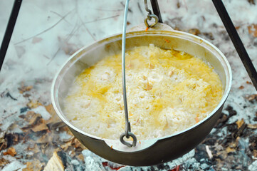 cooking pilaf in a cauldron over a fire. close-up.