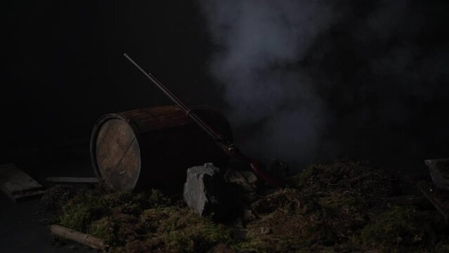 Ancient musket on a barrel among the smoke on the battlefield