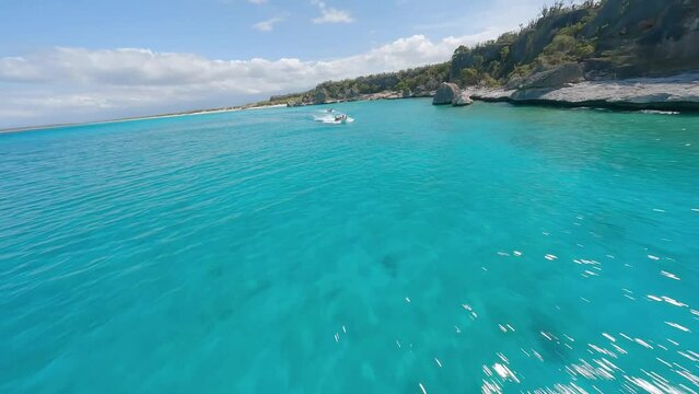 Spectacular fpv drone flight over blue colored Caribbean Sea and rocky coastline during sunlight