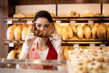 Fotobehang Portrait of bakery seller making funny smiling face with croissant in bakery shop. © littlewolf1989