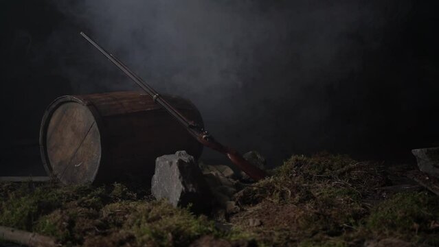 Ancient musket on a barrel among the smoke on the battlefield