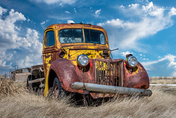 An abandoned vintage yellow and red truck without an engine on the Saskatchewan prairies